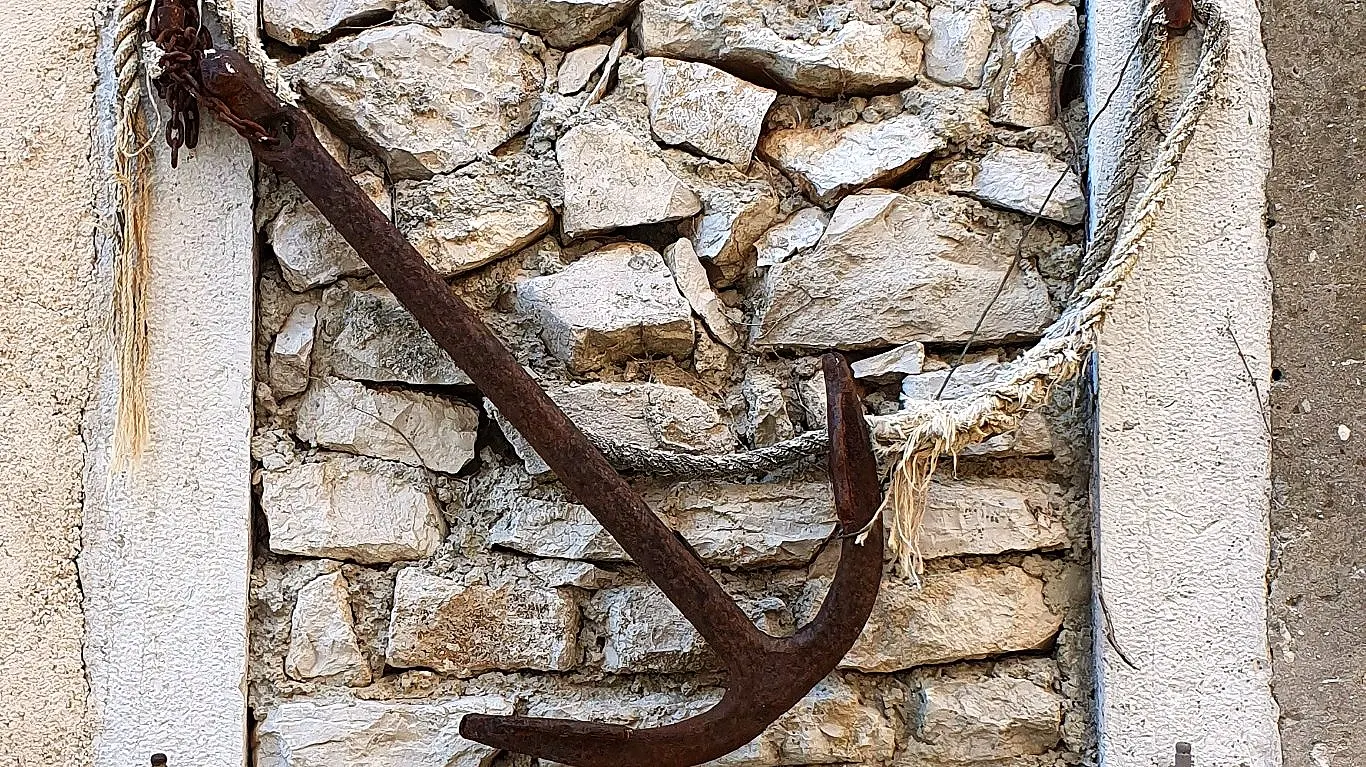 Old iron anchor on a stone wall